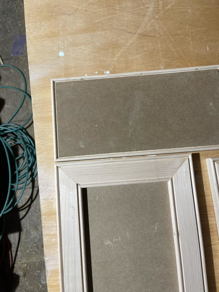 Unfinished wooden cabinet doors being prepared for installation, showcasing carpentry work by Wanderworks in Charleston, SC.