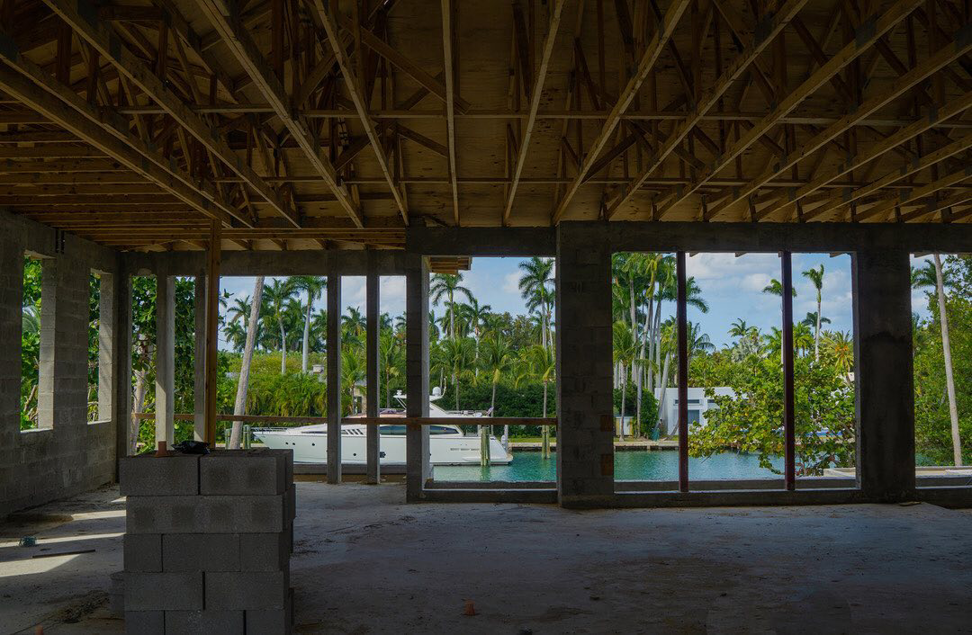 An unfinished interior of a waterfront home under construction, showing exposed joists and concrete blocks by Intelligent Construction Inc. in Miami, FL.