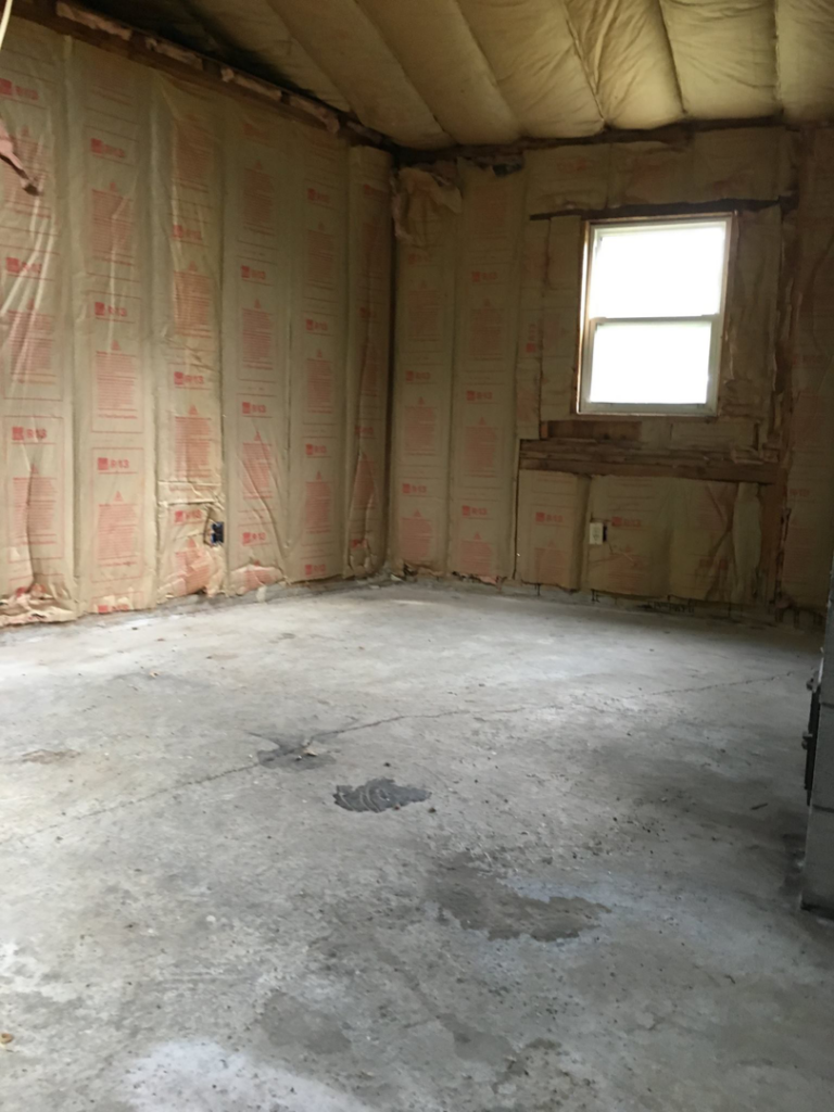 An unfinished room with wall insulation and a concrete floor, showing a project for Lemelin General Contracting in Fall River, MA.