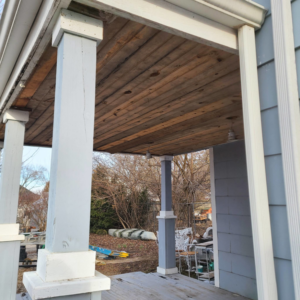 An older wooden porch ceiling showing exposed beams, ready for renovation by Dry Deck Ceilings KC in Kansas City, KS.
