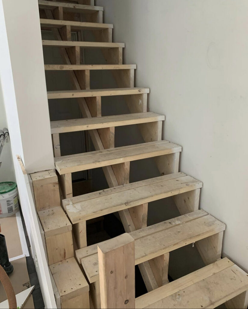 An unfinished wooden staircase showing the framing and structure, representing a carpentry project by Home pro handyman llc in Olathe, KS