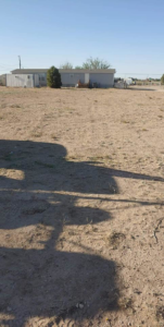 An unkempt yard with a house in the background, ready for cleanup by Handyman services inside or out in Carlsbad, NM.
