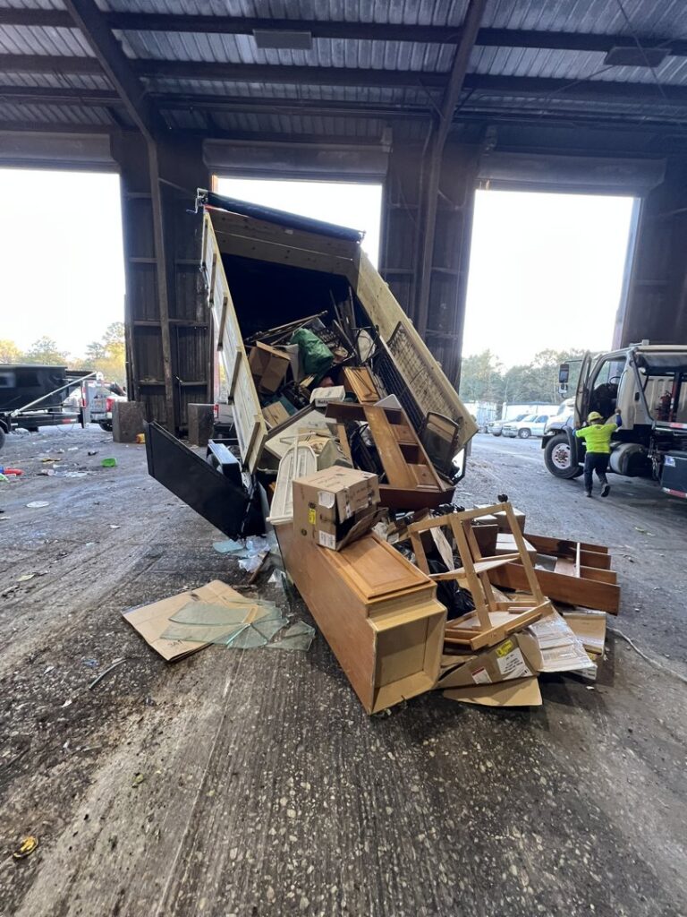A dump trailer unloading a variety of household junk and debris at a disposal facility by Tidy Loaders Junk Removal in Houston, TX.