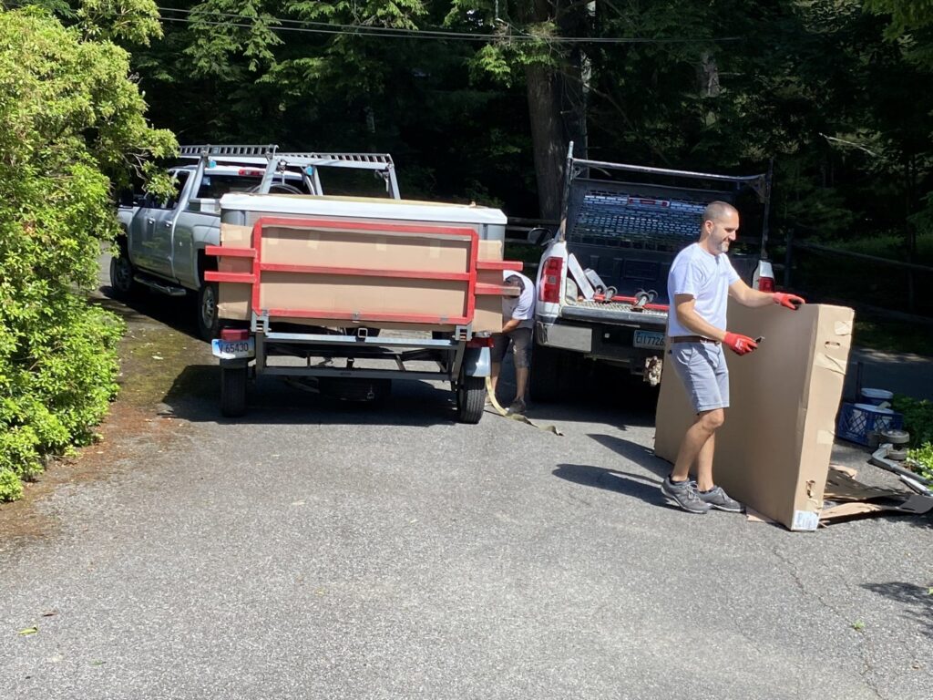 Hat City Pools team unloading a new, wrapped hot tub from a trailer for installation in Danbury, CT