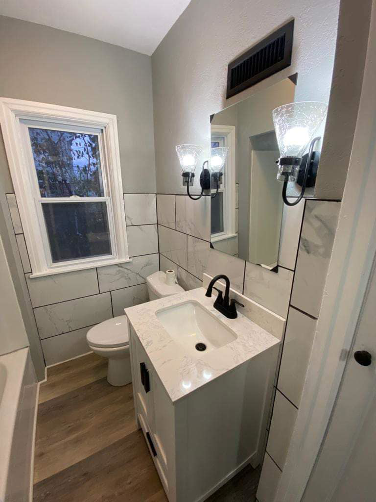 An updated bathroom featuring new wall tiles, a white vanity, mirror, and modern light fixtures by J&A Contractor LLC in Milwaukee, WI.
