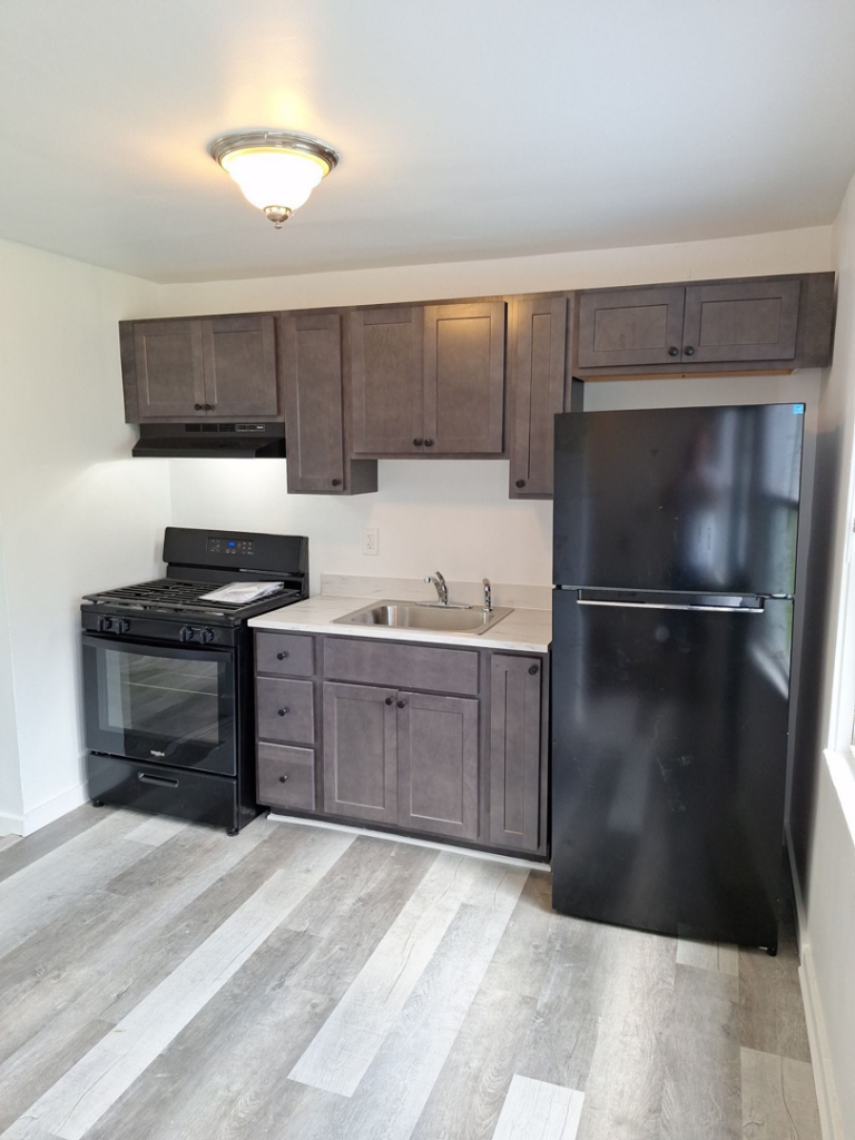An updated kitchen renovation with new gray cabinets and black appliances by Achieve Renovations in Pittsburgh, PA.