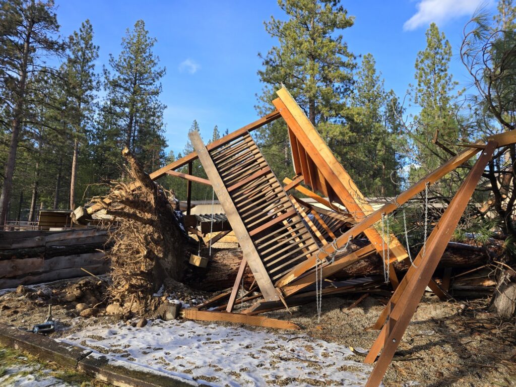 An uprooted tree has fallen and destroyed a wooden structure, a job for PJ's Tree Service in Missoula, MT.