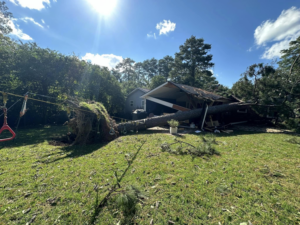 An uprooted tree fallen onto a house, showing the need for emergency tree removal by GNC Tree Service, LLC in Columbia, SC.
