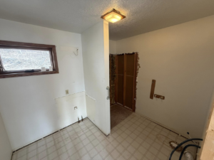 A utility room or bathroom renovation in progress with stripped walls and old tile floor by A&B Snow, Mow, and Contracting in Sioux City, IA.
