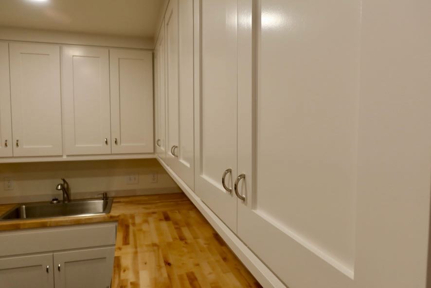 A utility room with custom white cabinets, wooden countertops, and a sink installed by Holaway Custom Builds in Fayetteville, AR.