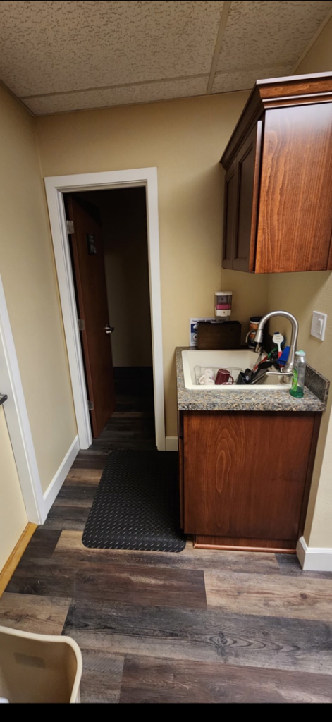 A utility sink with a wooden cabinet and new flooring installed by Leupitz Contractors Inc in Salem, OR.