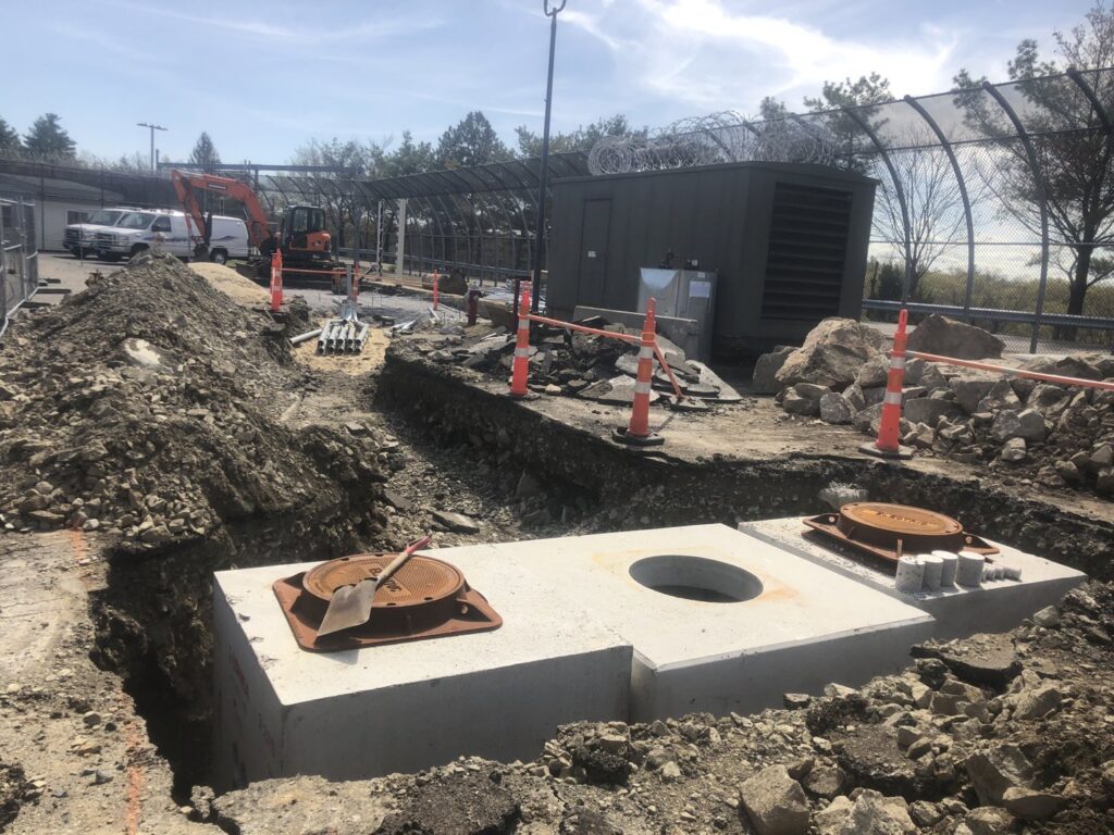 Pre-cast concrete utility structures being installed in an excavation trench by Solimini Excavation and Utility in Freetown, MA