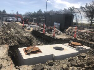 Pre-cast concrete utility structures being installed in an excavation trench by Solimini Excavation and Utility in Freetown, MA