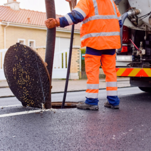 A utility worker using a hose and truck to service an open manhole for Utility Inspection Services, Inc. in Knoxville, TN.