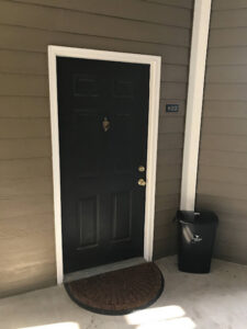 A black valet trash bin placed neatly beside an apartment door for A1 Valet Trash service in Atlanta, GA.