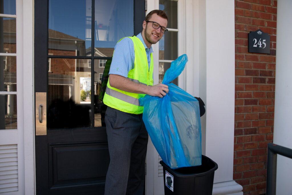An employee collecting valet trash from a residential doorstep for Retriever Valet Trash Service LLC in Memphis, TN.