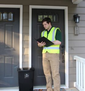 An A1 Valet Trash employee in a high-visibility vest standing next to a service bin in Atlanta, GA.