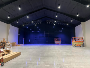 A large empty venue with installed lighting rigs and scissor lifts, showing an AV installation by Simon Pro Audio/Visual Integration in Oklahoma City, OK