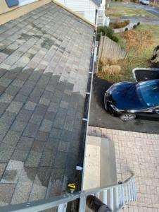 A view from a ladder showing a freshly cleaned gutter and roof, completed by DiEduardo Home Services LLC in Edison, NJ.