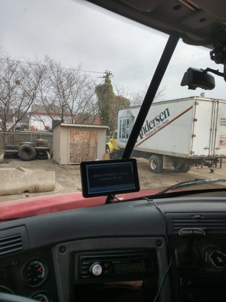 A view from inside a truck showing the recycling yard with a large trailer at Queen City Metal Recycling & Salvage in Charlotte, NC.