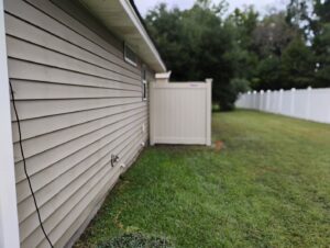 A newly installed light-colored vinyl privacy fence running alongside a residential house by Fence & Deck Connection, Inc. in Savannah, GA.