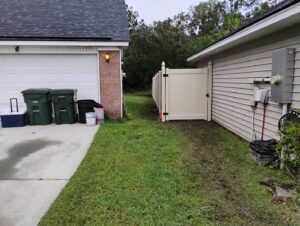 A newly installed light-colored vinyl privacy fence with a gate alongside a house by Fence & Deck Connection, Inc. in Savannah, GA.