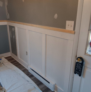 Wainscoting and a wooden top rail installed on a wall with a drop cloth on the floor by Carter's painting in Martinsburg, WV.