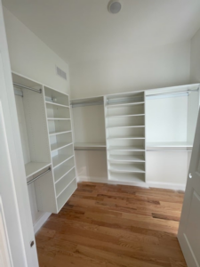 Walk-in closet with white shelving and hanging rods installed by Thermal Concepts, Inc in St. Louis, MO.