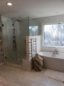 A luxurious bathroom remodel featuring a large walk-in glass shower and freestanding tub by Heritage Design & Remodel in Raleigh, NC.