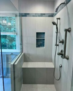 A walk-in shower with light-colored tiles, a built-in bench, and a niche with blue accent tiles, installed by The Bath Shop in Raleigh, NC.