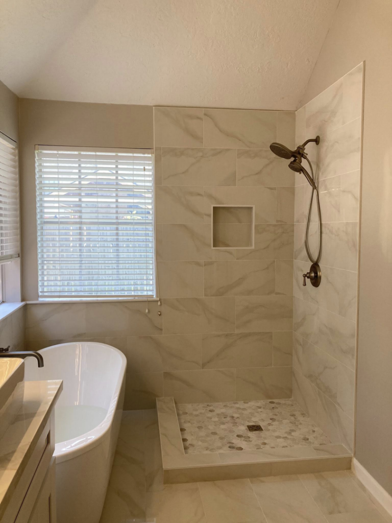 A renovated bathroom showcasing a walk-in shower with a niche and a sleek freestanding tub by J.C.Improvement in Katy, TX.