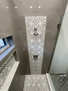 A modern walk-in shower with a striking geometric tile accent wall installed by Home Platinum Services, LLC in Plano, TX