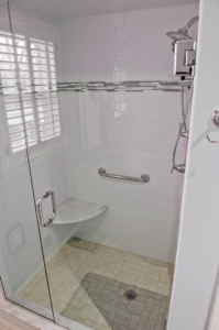 A modern walk-in shower with a glass door, white tile, and a grab bar by Glen E Stuckel Builder LLC in Louisville, KY.