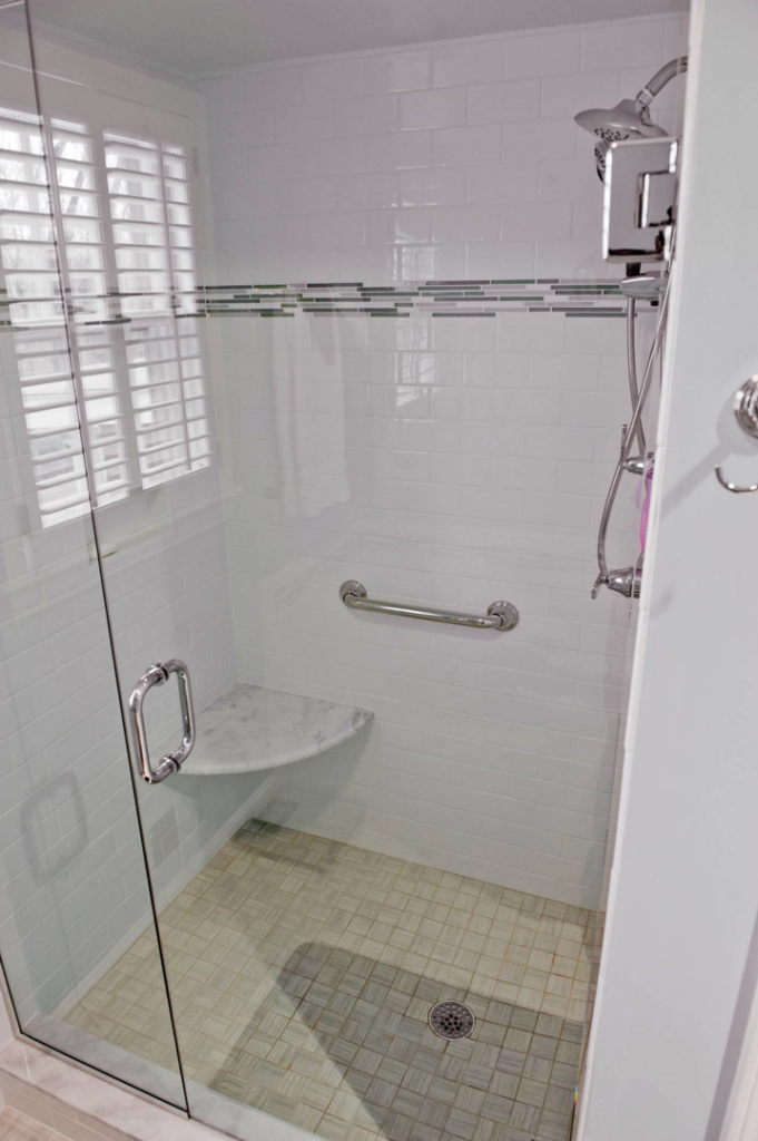 A modern walk-in shower with a glass door, white tile, and a grab bar by Glen E Stuckel Builder LLC in Louisville, KY.