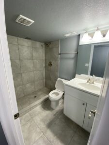 A newly installed walk-in tiled shower, toilet, and vanity in a remodeled bathroom by Advanced Remodeling Services in Elbert, CO.