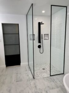A modern walk-in shower with black fixtures and white subway tile installed by NP General Contracting in Austin, TX.