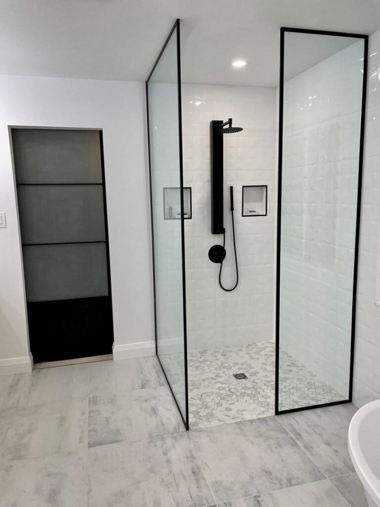A modern walk-in shower with black fixtures and white subway tile installed by NP General Contracting in Austin, TX.