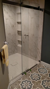 Modern walk-in shower with glass doors and marble-look walls installed by Coastal Contracting Services Inc., Virginia Beach, VA.