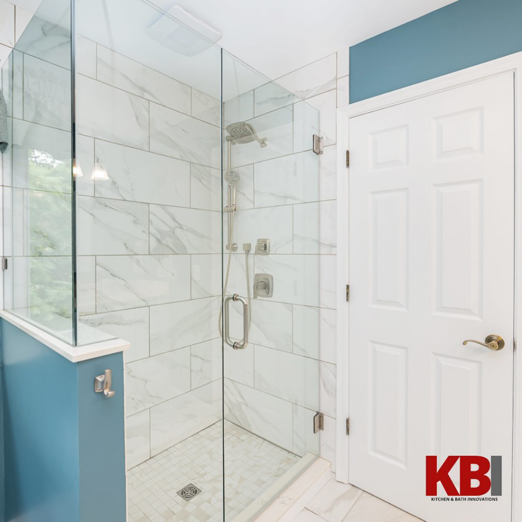 A modern walk-in shower with glass enclosure and white marble-look tiles installed by Kitchen and Bath Innovations in Cincinnati, OH