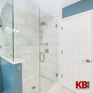 A modern walk-in shower with glass enclosure and white marble-look tiles installed by Kitchen and Bath Innovations in Cincinnati, OH