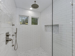 A newly installed walk-in shower with white subway tiles and a pebble floor, a service provided by Boyd's Custom Building in Charlotte, NC.