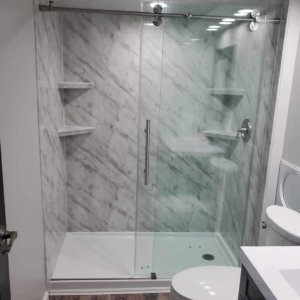 A newly installed walk-in shower with marble-look wall panels and a sleek glass door by Bath Pro in Florence, KY