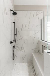 A modern walk-in shower with white marble-look tiles and sleek black fixtures, completed by Synergy Builders in West Chicago, IL.