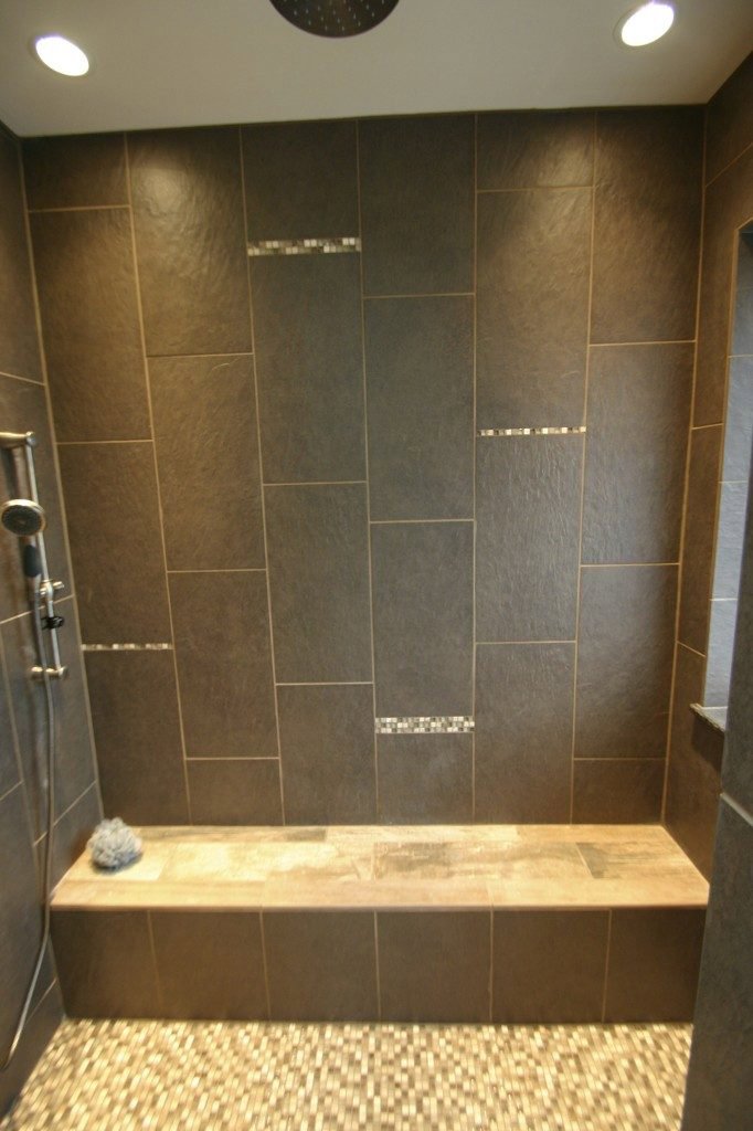 A walk-in shower with dark brown tiles and a built-in bench by Shafer Construction, LLC in Bethlehem, PA.