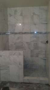 A newly installed walk-in shower with natural stone tiles by Gudiño's Tile and Natural Stone in Glendale, AZ