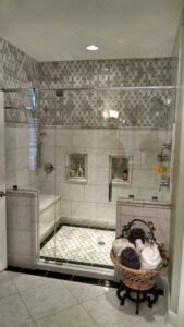A modern walk-in shower with intricate tile work and glass enclosure by Unique Construction Services in Knoxville, TN