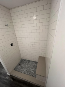 Detailed view of walk-in shower tiling with white subway tiles and a built-in bench by Roempagel Renovations LLC in South Bend, IN.