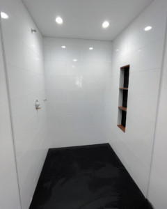Interior of a walk-in shower with white subway tiles and black hexagonal floor by Clean Cut Tile LLC in St. Louis, MO.