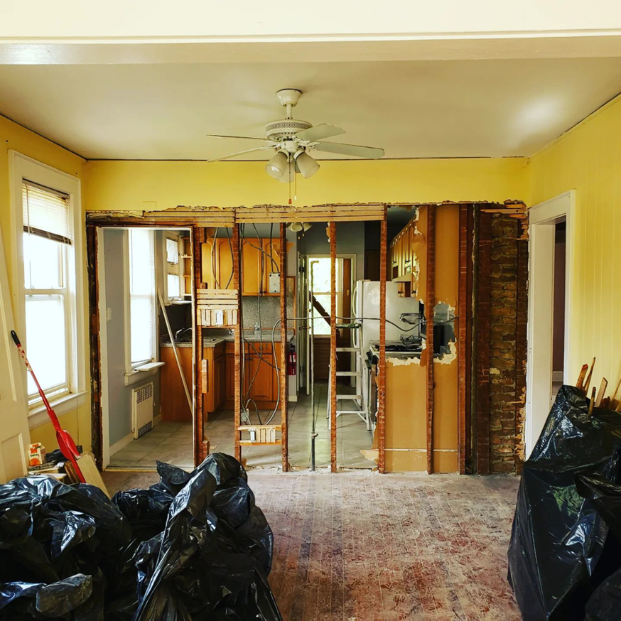 Wall demolition in a kitchen area with exposed brick and studs by CJM Builders Inc in Wilmington, MA.