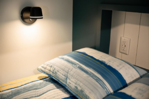 A newly installed wall-mounted light fixture and electrical outlet next to a bed by An Extra Hand in Indianapolis, IN.